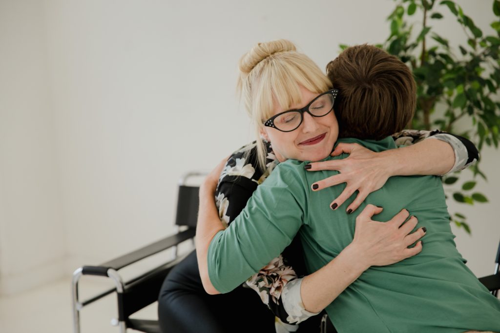 two people hugging and smiling sitting at real estate brokerage