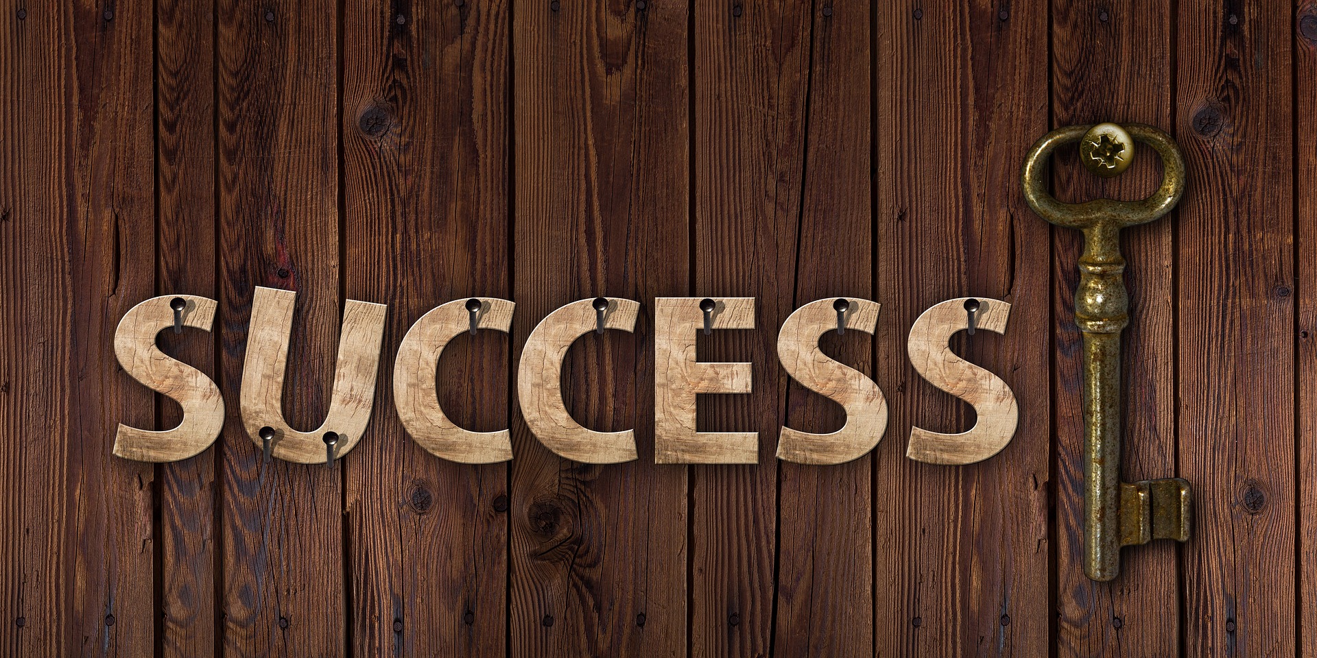 Success with key success wood cut out on key rings with wood in background old metal key